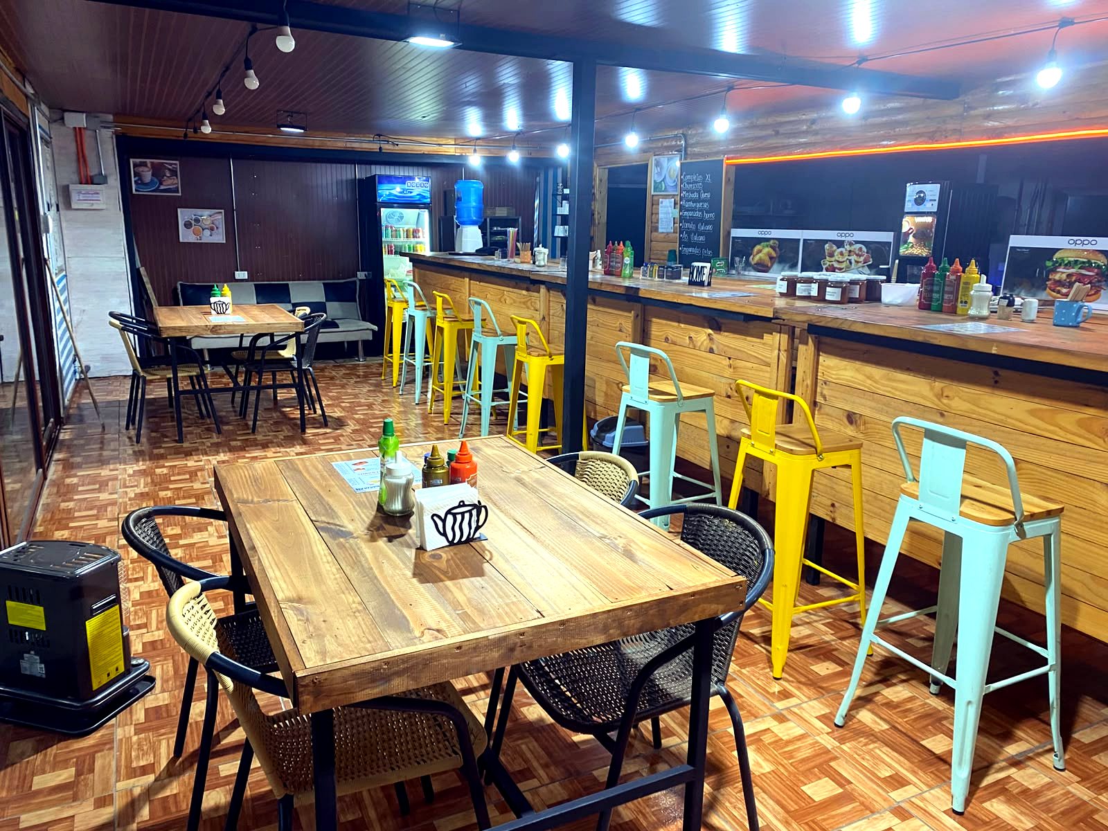 Salón interior de Amore Cafetería con mesas de madera y banquitos de colores